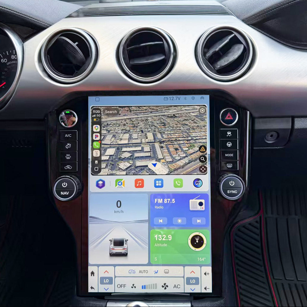 A large touchscreen car infotainment system mounted in the center console of a vehicle interior, showing a navigation map and media controls. The dashboard has silver trim and circular air vents, with black footwells and red stitching visible.