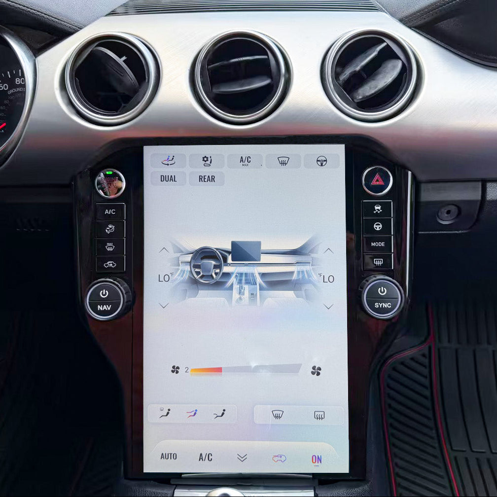 Close-up of a car interior dashboard with a large central touchscreen display showing climate control, mounted on a silver and black console with circular air vents.